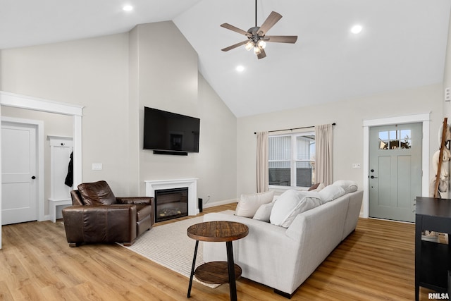 living room with ceiling fan, high vaulted ceiling, and light hardwood / wood-style flooring