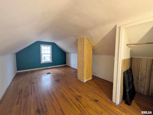 bonus room with dark hardwood / wood-style floors and vaulted ceiling