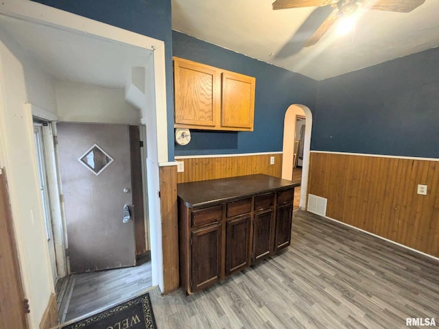 kitchen featuring wood-type flooring, ceiling fan, and wood walls