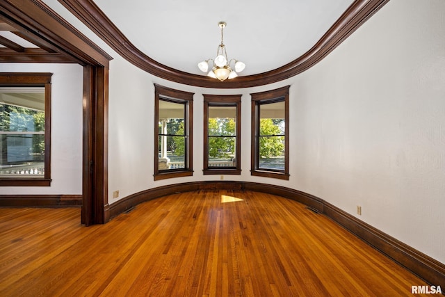 spare room featuring hardwood / wood-style flooring, ornamental molding, plenty of natural light, and a notable chandelier