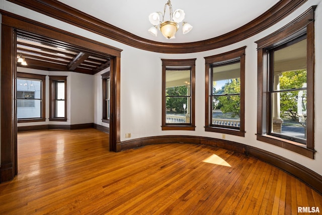 spare room featuring crown molding, beamed ceiling, a chandelier, and light wood-type flooring