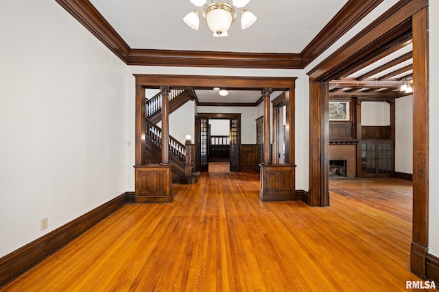 interior space with a brick fireplace, crown molding, hardwood / wood-style floors, and a chandelier