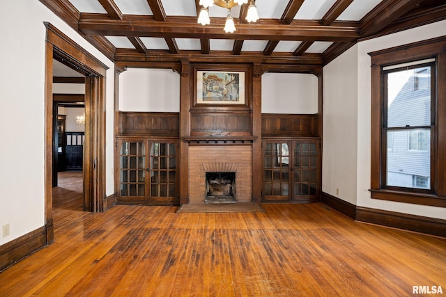 unfurnished living room with hardwood / wood-style flooring, a fireplace, beam ceiling, and a chandelier