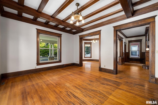 unfurnished room featuring wood-type flooring, coffered ceiling, a notable chandelier, crown molding, and beam ceiling