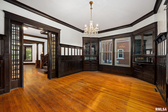 interior space with ornamental molding, wood-type flooring, and a chandelier