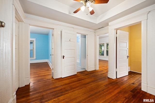 unfurnished bedroom featuring a raised ceiling, dark wood-type flooring, and ceiling fan