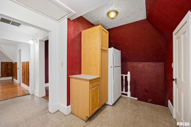 hallway featuring vaulted ceiling and a textured ceiling