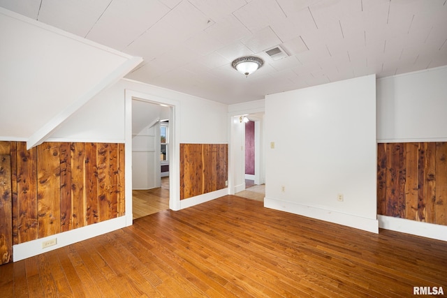 additional living space with hardwood / wood-style flooring and wooden walls