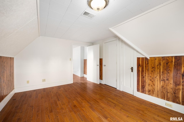 bonus room with vaulted ceiling, hardwood / wood-style floors, and wooden walls