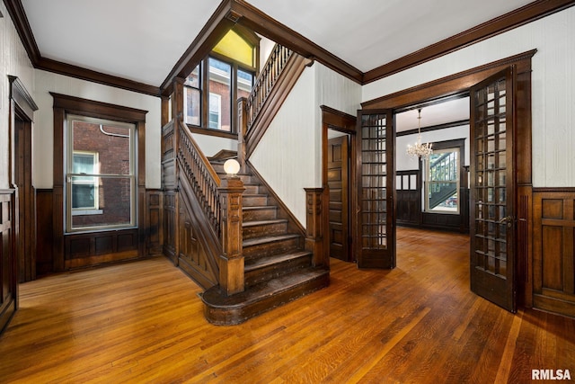 staircase featuring crown molding, hardwood / wood-style floors, and a notable chandelier