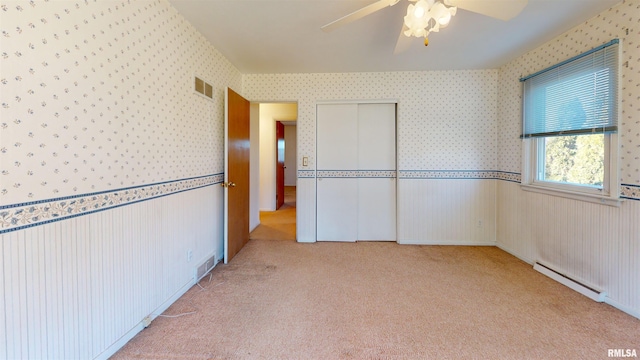 unfurnished room with a baseboard heating unit, light carpet, and ceiling fan