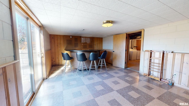 interior space featuring washer / dryer, a breakfast bar area, and wood walls