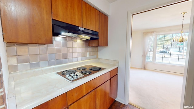 kitchen with white cooktop, an inviting chandelier, hanging light fixtures, baseboard heating, and backsplash