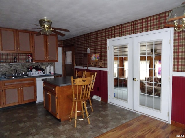 kitchen featuring sink, ceiling fan, white dishwasher, a kitchen island, and french doors