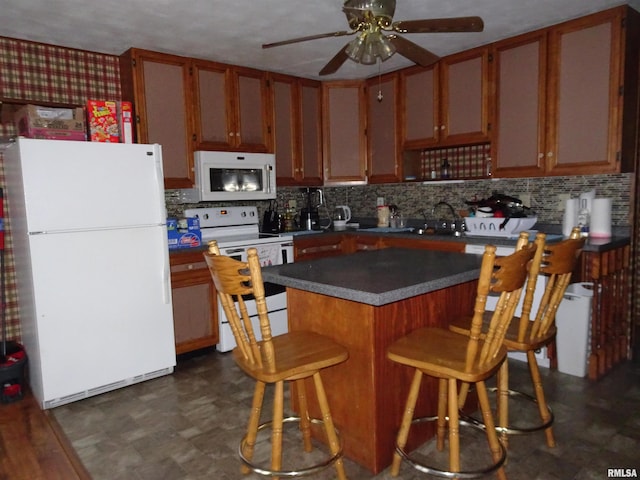 kitchen featuring backsplash, white appliances, a kitchen breakfast bar, and ceiling fan