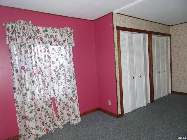 unfurnished bedroom with dark carpet and multiple closets