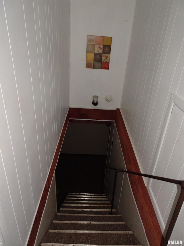 stairway featuring wood walls