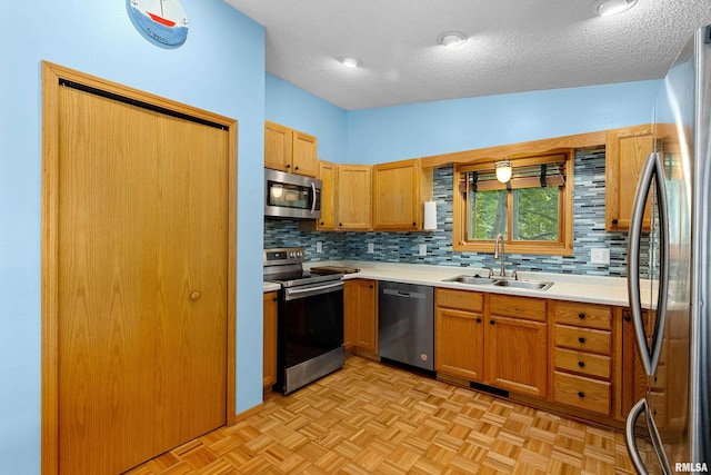 kitchen featuring stainless steel appliances, tasteful backsplash, sink, and light parquet floors