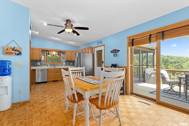 dining area with ceiling fan, light parquet flooring, vaulted ceiling, and a textured ceiling