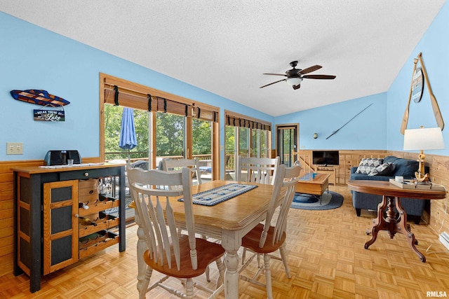 dining space featuring light parquet flooring, a textured ceiling, and wood walls