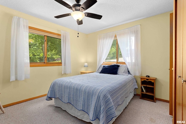 bedroom featuring ceiling fan, light colored carpet, and a textured ceiling