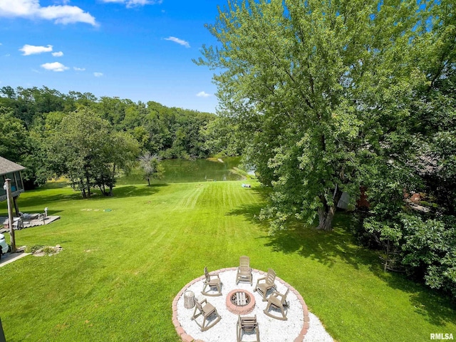 view of yard featuring a water view, an outdoor fire pit, and a patio area