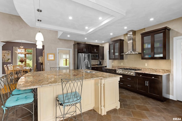 kitchen featuring a large island, a tray ceiling, stainless steel appliances, and wall chimney exhaust hood