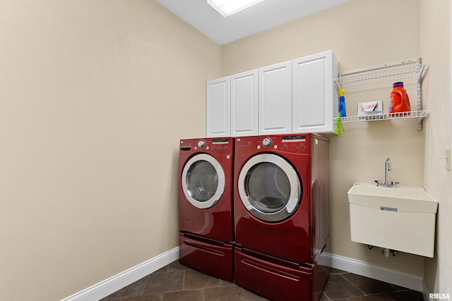 clothes washing area featuring cabinets, independent washer and dryer, dark tile patterned flooring, and sink