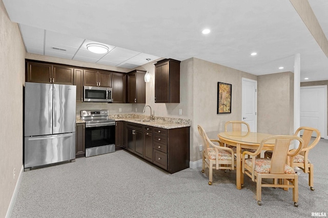 kitchen with dark brown cabinetry, sink, light colored carpet, and stainless steel appliances