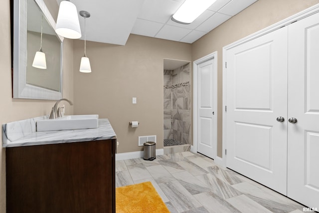 bathroom with vanity, a drop ceiling, and a tile shower