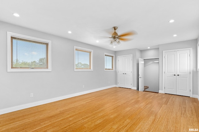 unfurnished bedroom featuring multiple closets, ceiling fan, and light wood-type flooring