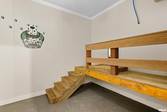 stairway with ornamental molding and concrete floors