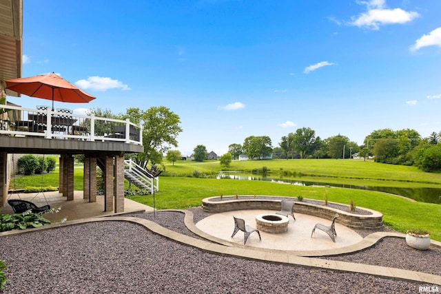 view of yard with a patio, a deck with water view, and an outdoor fire pit