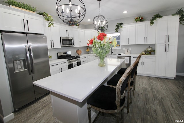 kitchen with white cabinetry, a center island, hanging light fixtures, dark hardwood / wood-style floors, and stainless steel appliances