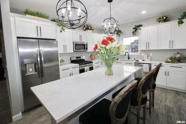 kitchen featuring hanging light fixtures, appliances with stainless steel finishes, a center island, and white cabinets