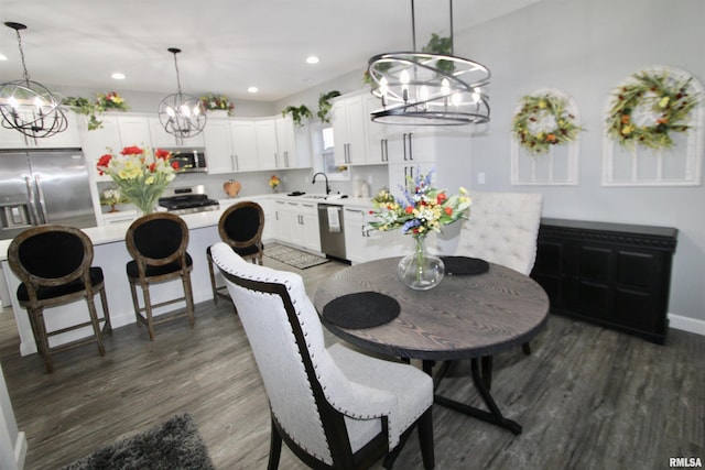 dining room with dark wood-type flooring, sink, and an inviting chandelier