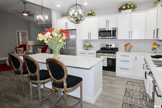 kitchen with stainless steel appliances, white cabinetry, a kitchen bar, and decorative light fixtures