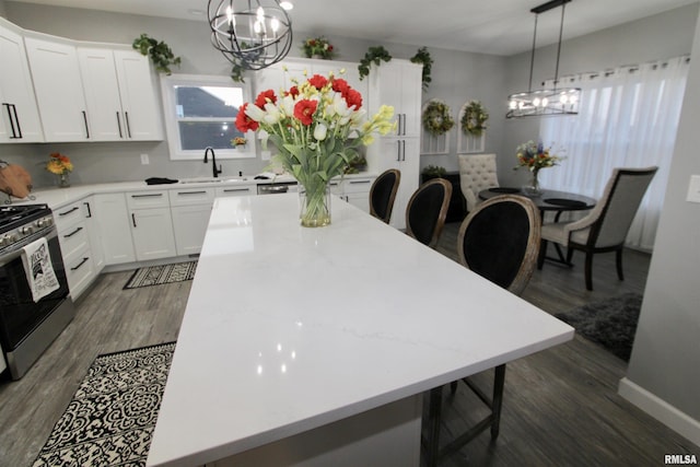 kitchen featuring pendant lighting, a notable chandelier, gas stove, and white cabinets