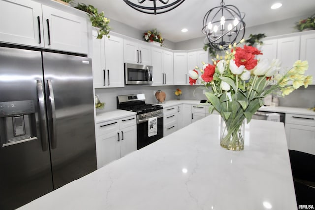 kitchen featuring stainless steel appliances, white cabinetry, hanging light fixtures, and light stone countertops