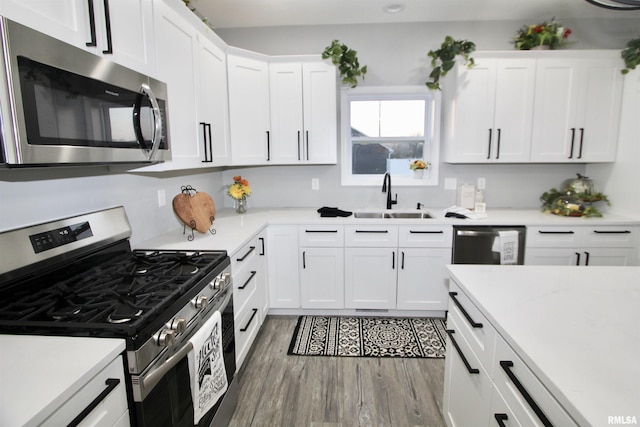 kitchen featuring white cabinetry, appliances with stainless steel finishes, sink, and hardwood / wood-style floors