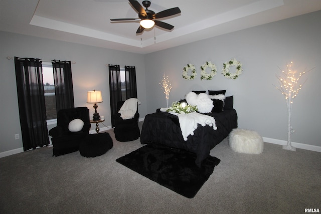 carpeted bedroom featuring a tray ceiling and ceiling fan