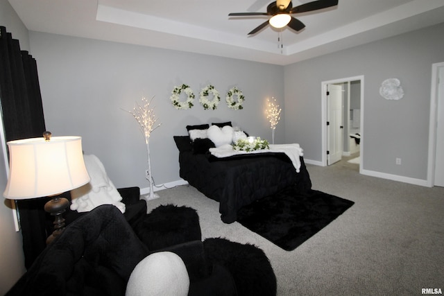 bedroom featuring connected bathroom, a tray ceiling, and light carpet