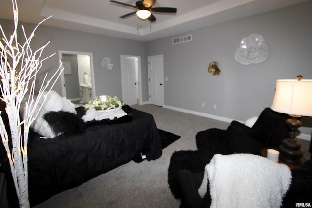 carpeted bedroom with connected bathroom and a raised ceiling