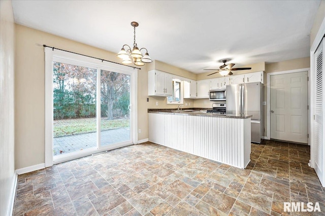 kitchen featuring pendant lighting, white cabinetry, stainless steel appliances, ceiling fan with notable chandelier, and kitchen peninsula