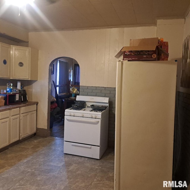 kitchen featuring cream cabinets, wooden walls, and white appliances