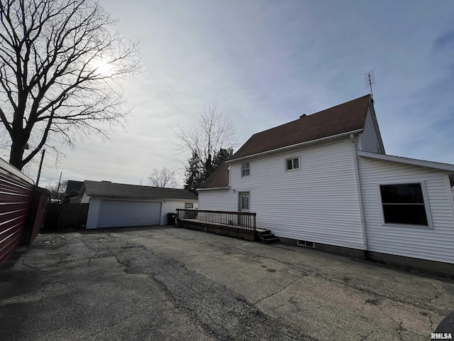 view of side of home featuring a garage, an outdoor structure, and a deck