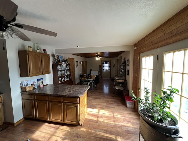 kitchen with ceiling fan, light hardwood / wood-style floors, kitchen peninsula, and a textured ceiling