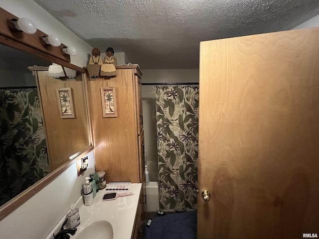 bathroom with vanity, shower / bath combination with curtain, and a textured ceiling