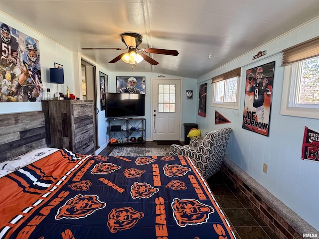 bedroom with multiple windows, dark tile patterned floors, lofted ceiling, and ceiling fan