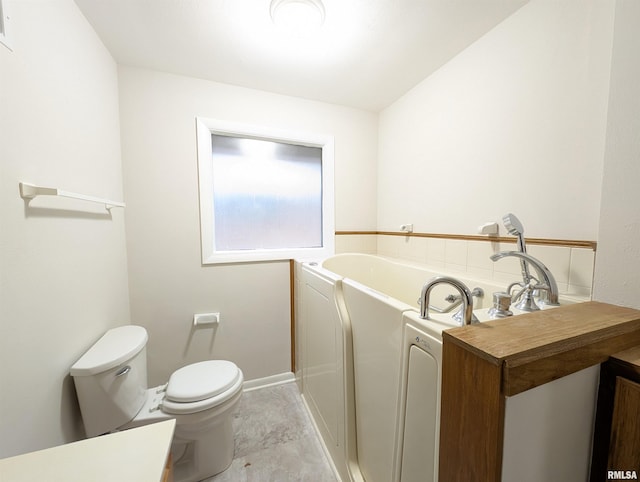 bathroom featuring a tub to relax in, toilet, and vanity